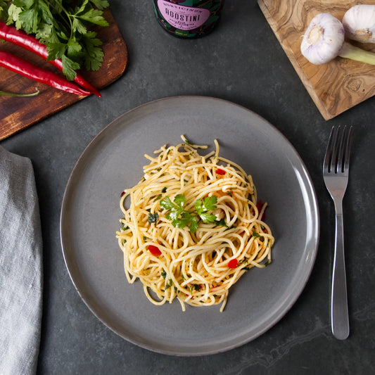 Der italienische Pasta-Klassiker Spaghetti Aglio, Olio e Peperoncino wird frisch zubereitet auf einem grauen Teller serviert.